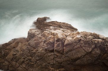 Rock in breaking waters in long exposure