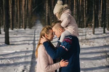 Fototapeta premium side view of beautiful happy young family spending time together in winter forest