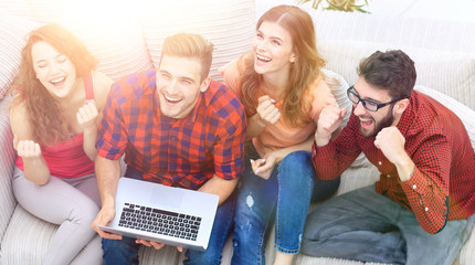 group of friends watching a video on a laptop and laughing