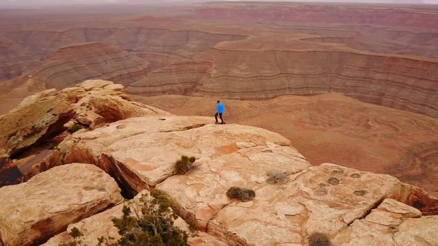 Aerial shot of a man hiking along the edge of amazing rock formations in Utah.