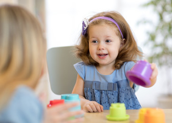 2 year-old child playing with educational cup toys at home.