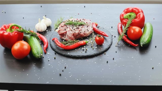 Chef cooking meat with salt spices and fresh vegetables on black wooden table. nobody apetizing tasty meal organic products ingredients recipe dish close-up modern recipe book garlic chilli pepper