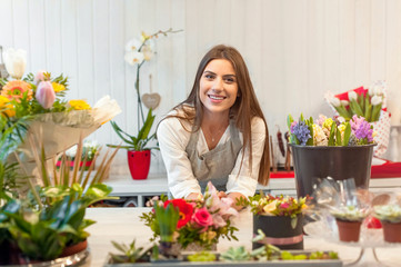 Smiling woman florist small business flower shop owner, at counter, looking friendly at camera.