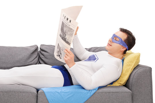 Superhero lying on a sofa and reading a newspaper