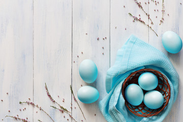 Blue easter eggs in small basket on wooden background