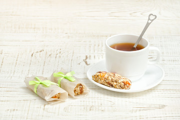 Cup of tea and few bar of muesli. White wooden background