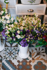 Beautiful fresh flowers in pots in a flower shop with beautiful decorated vintage floor.