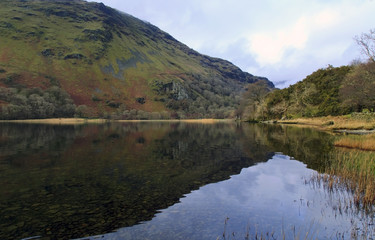 Fototapeta na wymiar Clouds and mountains reflected in a still lake, Llyn Gwynant, Snowdonia, Wales