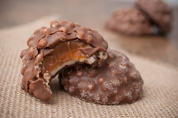 closeup of bitten marshmallows coated with chocolate on wooden table background