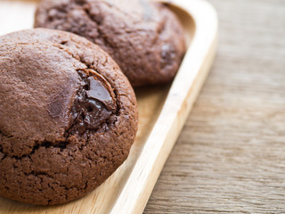 Homemade soft dark chocolate brownie cookies placed on a wooden plate. The cookies is look good and delicious.