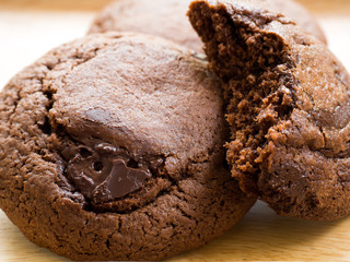 Homemade soft dark chocolate brownie cookies placed on a wooden plate. Close Up cookies are bitten. Look good and delicious.
