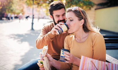 Couple eating a sandwich outdoors. Dating, consumerism, food, lifestyle concept