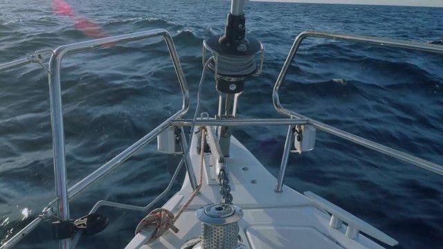 Anchor chain cable, jib furler on bow of yacht and view of pod of dolphins and beautiful sunset.