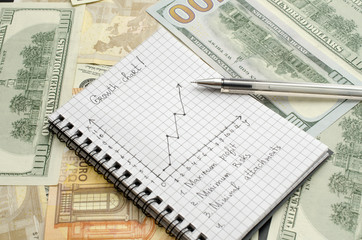 notepad with growth chart, pen, money