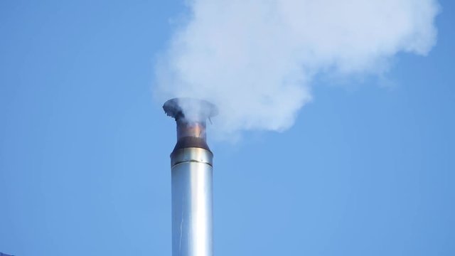 Smoking pipe on roof in a cold winter day. winter smoke comes from the chimney at home