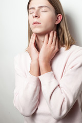 Androgynous young man with pink sweater on white background. Close eyes