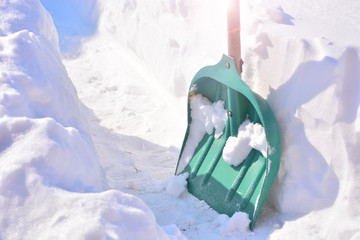 Shovel for snow removal stands in a deep snow.  Concept of a snow removal after a big snowfall.