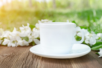 White mug and apple flowers on a wooden background. Side view