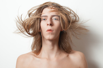 Androgynous young man with hair on the wind on white background
