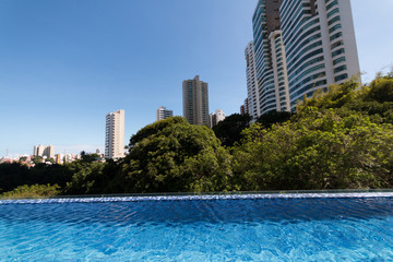 Fototapeta na wymiar Infinity pool with trees and buildings in the background