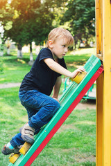 Fototapeta na wymiar Cute blond boy at playground outdoors.