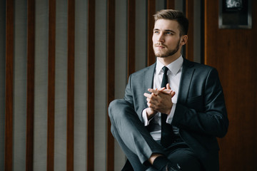 Young handsome successful boss sitting in a leather armchair in luxury fashionable interior...