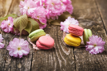 Pink sakura flowers with delisious macarons on dark wooden background , copy space, selective focus.