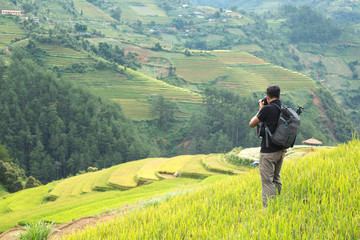 Fototapeta na wymiar backpack photographer taking landscape photo of rice terrace in Vietnam