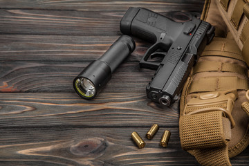 black pistol, flashlight and cartridges on a brown wooden