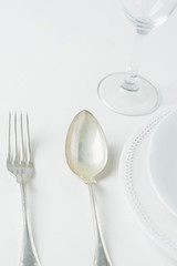 White Vintage Empty Plates Unpolished Silver Fork Spoon Wine Glass on Concrete Tabletop. Minimalist Japanese Style Table Setting. Template for Poster Banner Cooking Workshop Course. Easter Christmas
