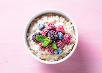 Oatmeal cereal with milk and berries top view.
