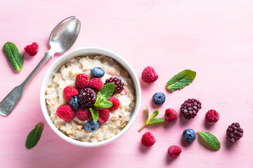 Oatmeal cereal with milk and berries top view.