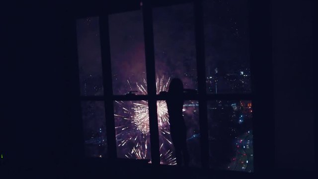 The Child Looks At Fireworks From Panoramic Window Of Apartment Located On High Floor Of Skyscraper. 4K