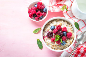 Oatmeal porrige with milk and berries top view.