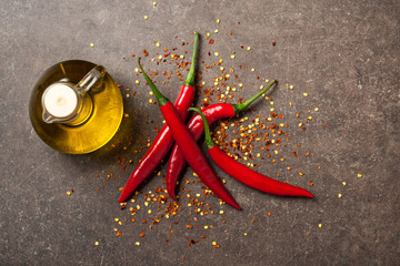 Red chili pepper and pitcher of oil on stone background