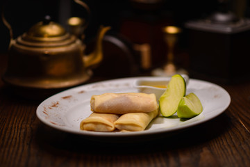pancakes with a filling and a green apple, in the background a kettle