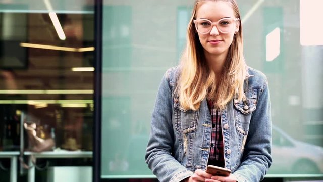 Portrait of cute prety, young woman sitting on the bench in the city
