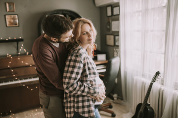 Pregnant woman and happy man in the house