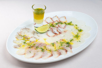 Fish assortment and a glass of oil with greens