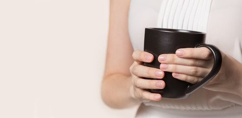 Female hands holding dark coffee cup