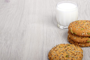 The composition of biscuits and a glass jar with yogurt or milk. Cookies and milk on a white wooden background. Tasty fresh cereal cookies with seeds. healthy Breakfast