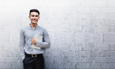 Happy Friendly Young Businessman standing at the Wall, Smile and holding a Digital Tablet, Lifestyle of modern male. Looking at camera