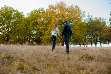 Obraz premium Young couple holding hands on a sunday afternoon going for a walk in the forest, in autumn season.