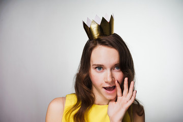 funny young blue-eyed girl in a yellow dress is waiting for Mother's Day, on her head is a golden...