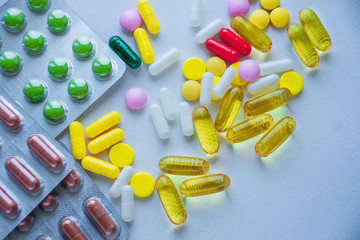 tablets, capsules, vitamins of different colors on a metallic background of gray color