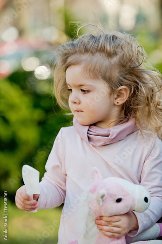Child With Long Blond Hair Hold Comb And Toy Horse Stock Photo