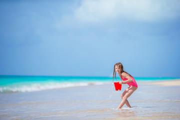 Fototapeta na wymiar Adorable little girl playing with beach toys in shallow water