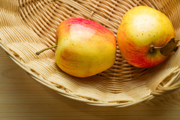 two fragrant ripe apples lie in a wicker basket