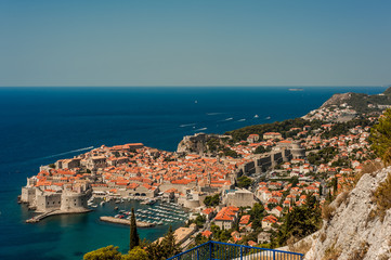 Naklejka na ściany i meble Spectacular picturesque view on the old town (medieval Ragusa) and Dalmatian Coast of Adriatic Sea. Picture taken from the mountain trails above Dubrovnik citadel, Famous European Travel Destination.