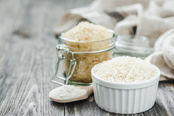 Rice and flour in glass jars on wooden rustic background. Selective focus, space for text. 
